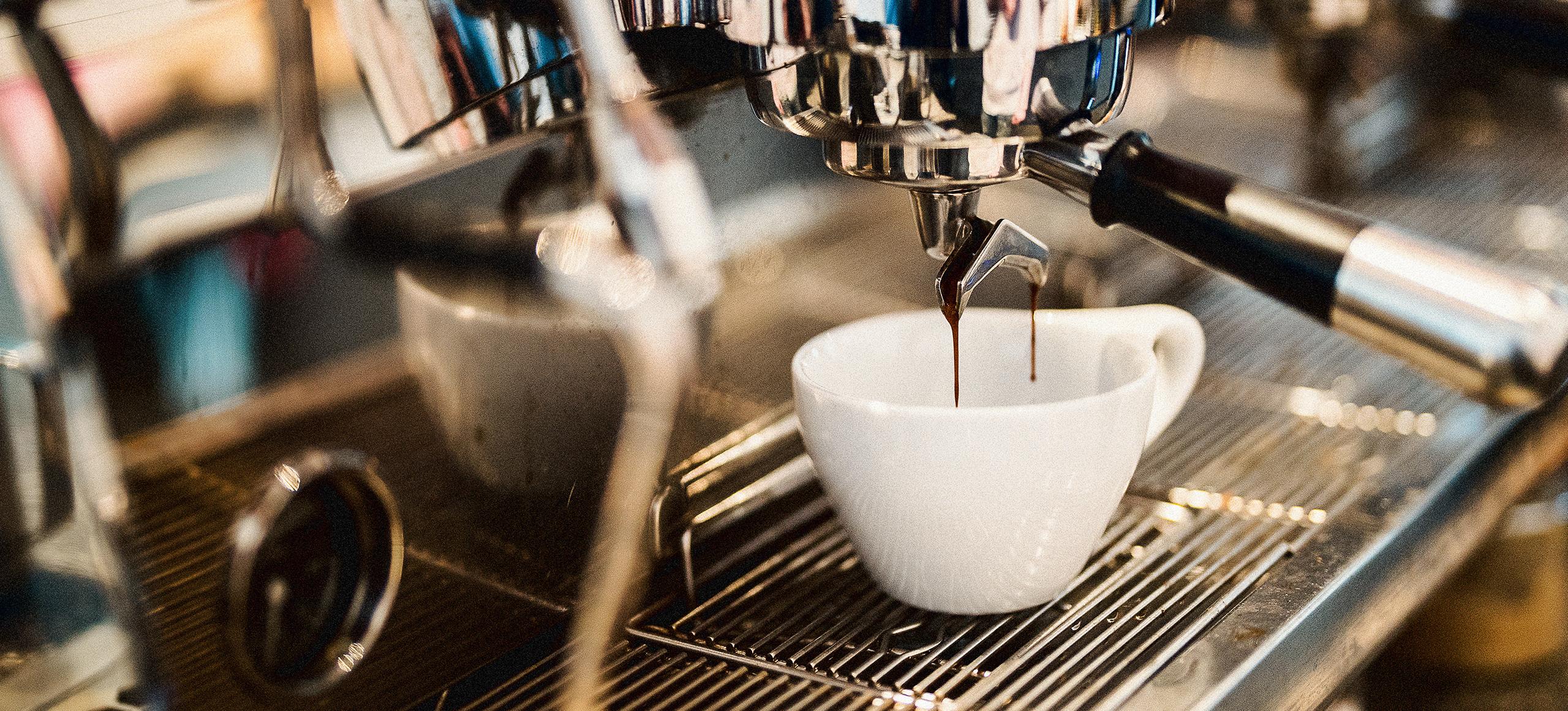 Coffee poring into a cup from the coffee machine.