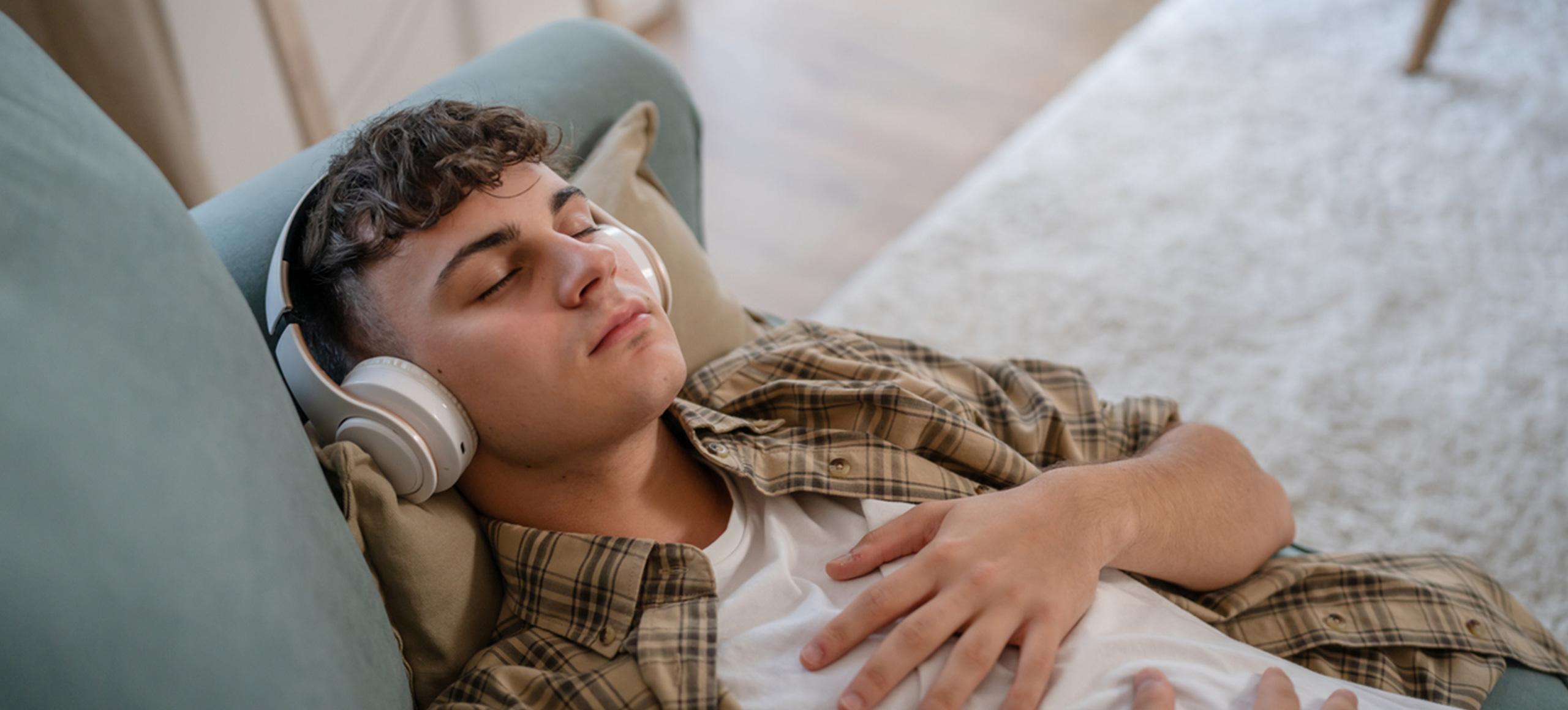 Boy sleeping peacefully on the sofa with headphones on