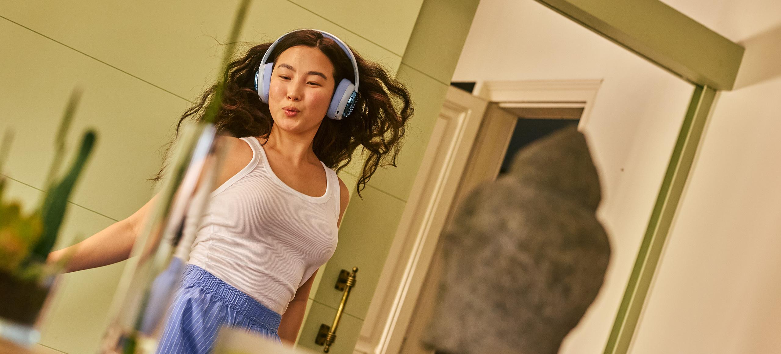 Girl dancing around her home with headphones on