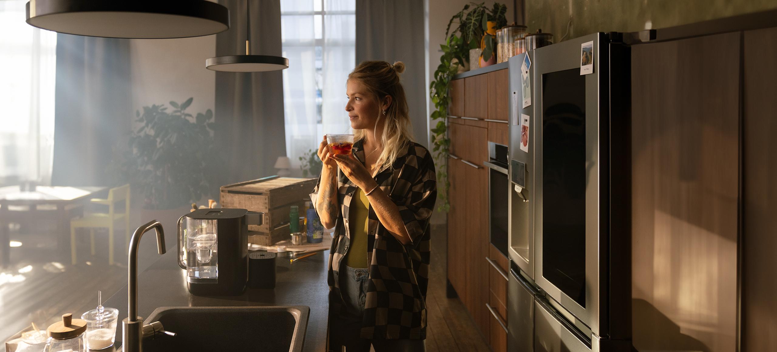 Relaxed woman drinking tea next to BRITA Cube