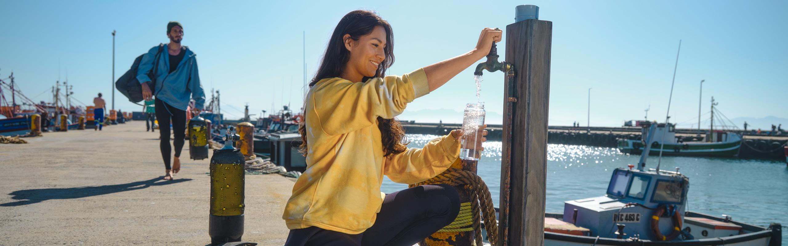A woman fills water into a bottle at a public water tap