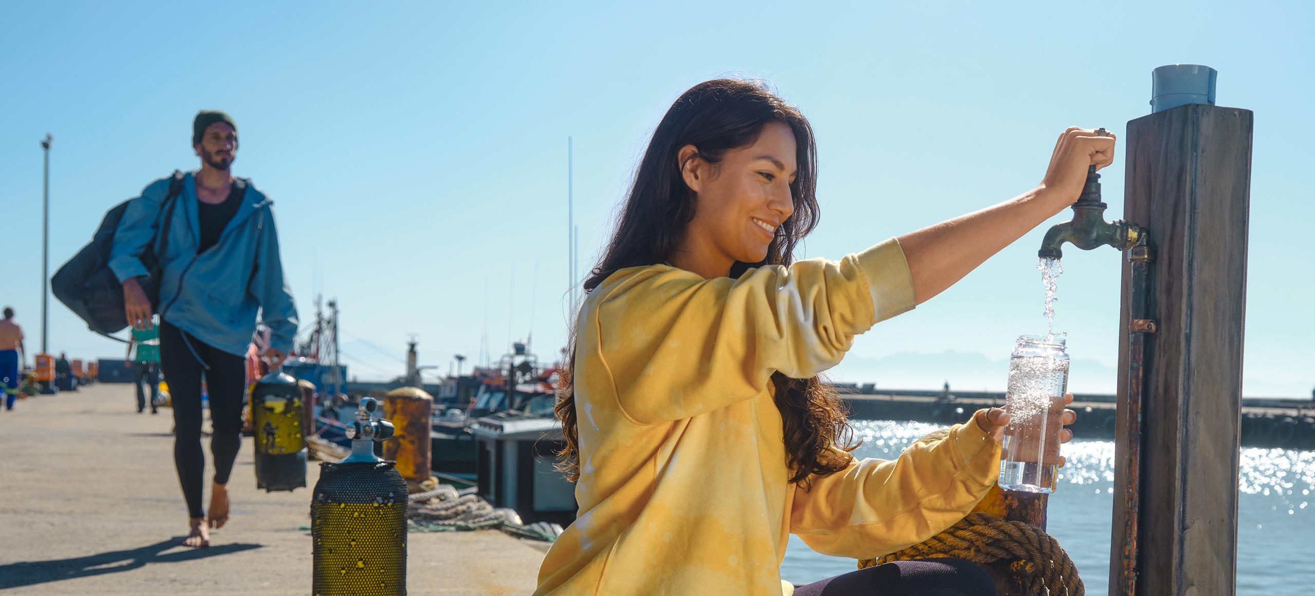 Woman pouring tap water into BRITA water filter bottle